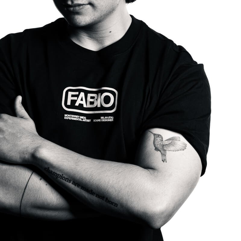 Man with crossed arms showing a hummingbird tattoo on his bicep